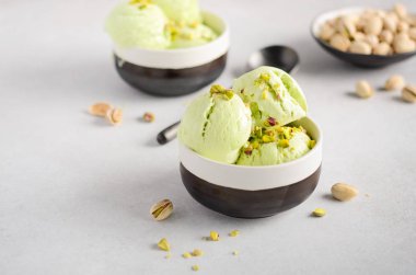 Gri beton zemin üzerine bir kase fıstık dondurma.