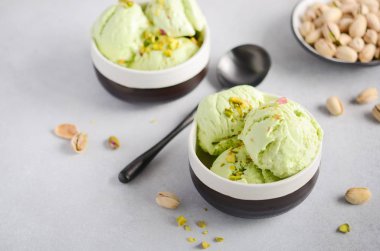 Gri beton zemin üzerine bir kase fıstık dondurma.