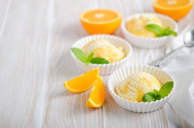 Beyaz ahşap masa üzerinde bir kase turuncu dondurma.