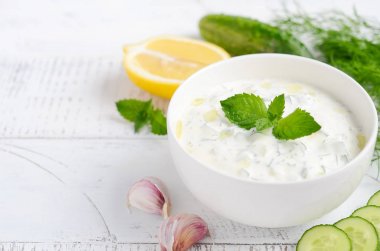 Yunan dip sosu veya soyunma tzatziki ve malzemeler beyaz ahşap masa üzerinde zeytinyağı ve nane ile dekore 