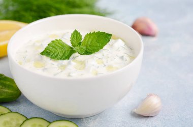 Yunan dip sosu veya mavi arka plan üzerinde zeytinyağı ve nane ile dekore edilmiş soyunma tzatziki.