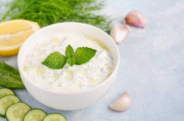 Yunan dip sosu veya mavi arka plan üzerinde zeytinyağı ve nane ile dekore edilmiş soyunma tzatziki.