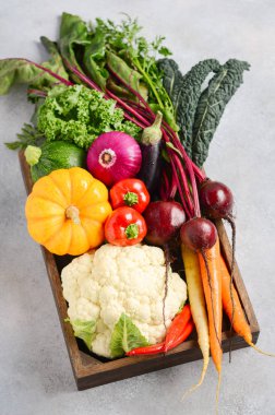 Gri beton arka plan üzerinde ahşap kutu taze organik sebzeler.