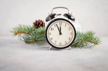 Yeni yıl ve Noel konsepti. Gri beton arka plan üzerinde siyah çalar saat ve köknar dalları.