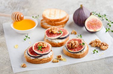 Bruschetta taze ricotta peyniri, incir, fındık, kekik ve bal gri beton arka plan üzerinde.