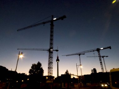 Alacakaranlıkta İnşaat vinçleri ile Cityscape Berlin. Fernsehturm arka planda, televizyon kulesi Alexanderplatz Mitte bölgesinde yakın