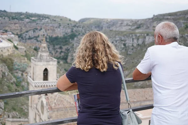 Unrecognizable back turned people looking at the famous Sassi di Matera, two districts of the Italian city of Matera, Basilicata, well-known for their ancient cave dwellings