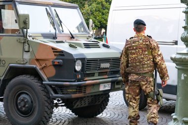 Verona, Italy - September 5, 2018: Back turned soldier in camouflage standing beside a military truck clipart