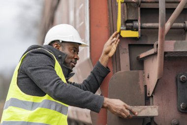 Afro-Amerikan mekanik emniyet donanımları (kask ve ceket) kontrol dişli tren giyiyor