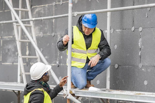 Ingénieurs Civils Avec Casque Veste Jaune Vérifiant Les Dessins Techniques Image En Vente