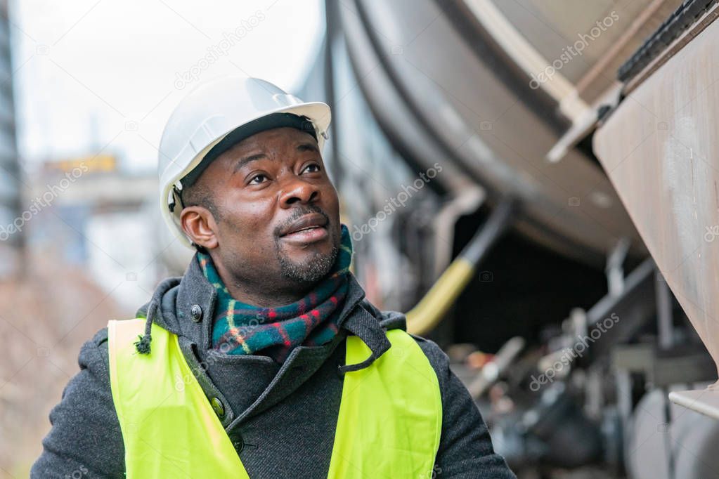 African American railroad engineer wearing safety equipment (helmet and jacket) checking gear train