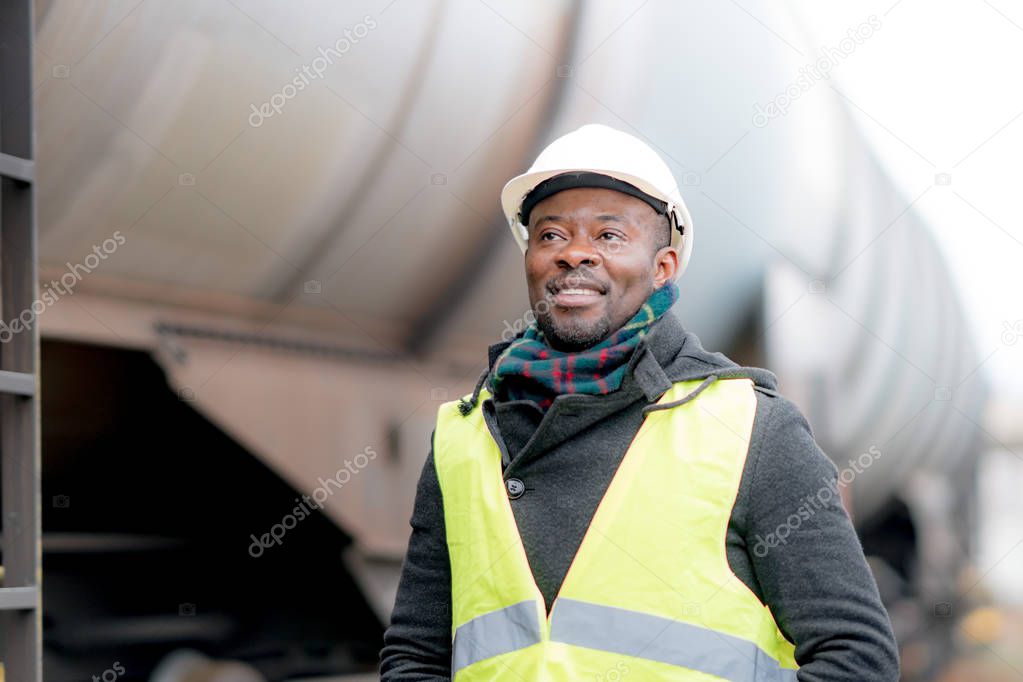 Portrait of a smiling and satisfied African American engineer wearing protective workwear posing on construction site