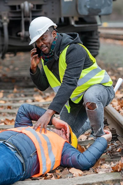 Railroad engineer injured in an accident at work on the railway tracks. Calling for help