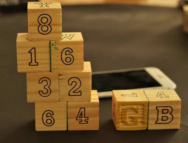 Wooden cubes forming the numbers 8, 16, 32, 64 and the acronym GB for Gigabyte, measuring the Rom, the phone's internal memory