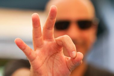 Caucasian man with sunglasses making ok sign at camera. Selective focus clipart