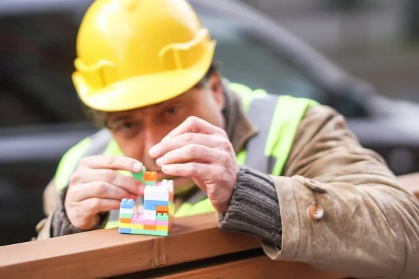 Concentrated civil engineer using multicoloured plastic construction toy building blocks or toy bricks. Outdoors