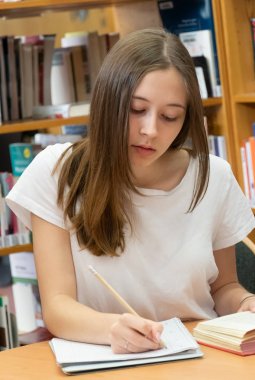 Okul kütüphanesinde ödevini yapan öğrenci