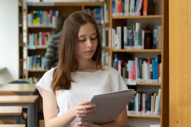 Okul kütüphanesinde okuyan konsantre bir kızın portresi