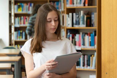 Okul kütüphanesinde okuyan konsantre bir kızın portresi
