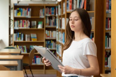 Okul kütüphanesinde okuyan konsantre bir kızın portresi