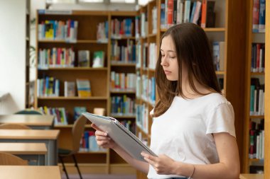 Okul kütüphanesinde okuyan konsantre bir kızın portresi