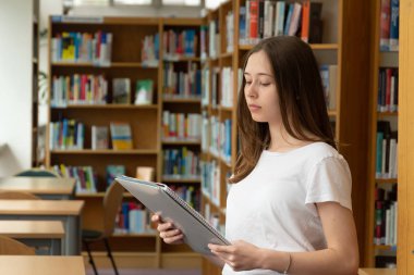 Okul kütüphanesinde okuyan konsantre bir kızın portresi