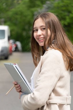 Kameraya bakarak poz veren sınıfa giderken gülümseyen üniversite öğrencisi