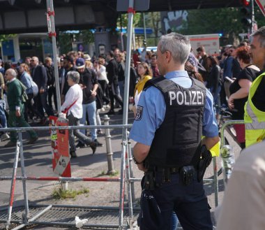 Berlin, Almanya - 1 Mayıs 2019: Bir gösteri sırasında kalabalığın içinde taktik gilet ve sarı önlük giyen güvenlik görevlileri geri döndü