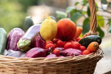 Hasır sepet taze ve olgun çiftlik sebze dolu: patlıcan, kabak, havuç, domates, limon ve arpacık