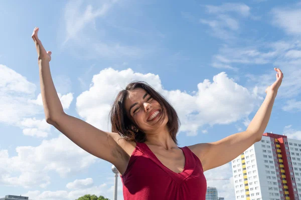 Blissful woman celebrating with outstretched arms the cityscape of Berlin