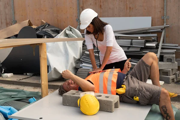 Nurse or paramedic providing cardiopulmonary resuscitation (CPR) on a construction worker injured in an accident at work. Outdoors