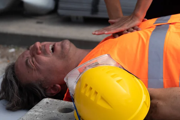 Cropped image of a paramedic\'s hands providing cardiopulmonary resuscitation (CPR) on a construction worker injured in an accident at work