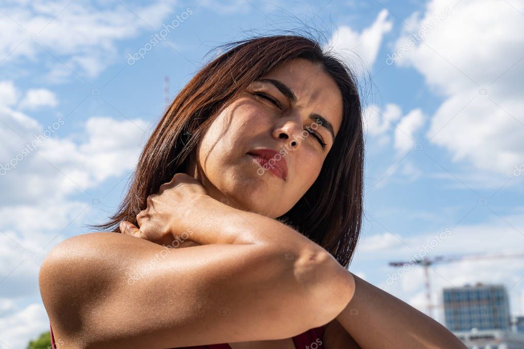 Neck pain or stiffness. Young brunette woman massaging her suffering neck