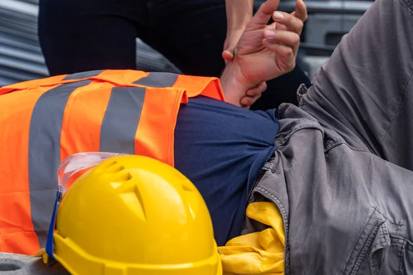 护理人员双手检查一名卧倒在地建筑工人在工作时受伤的脉搏率的裁剪图像 — 图库照片