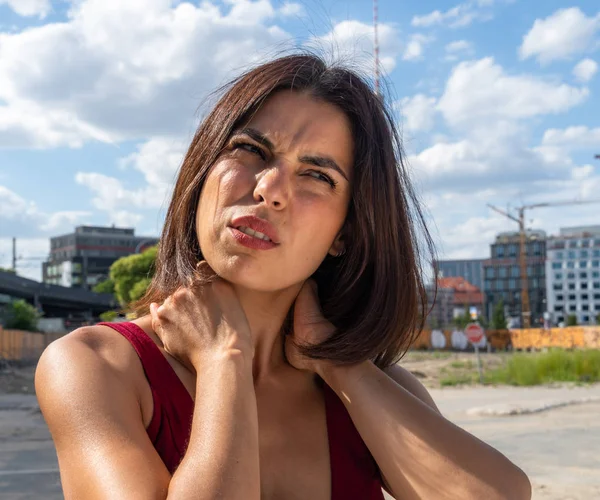 Neck muscle strain. Suffering brunette woman massaging her stiff neck