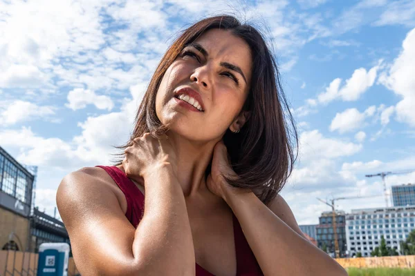 Neck muscle strain. Suffering brunette woman massaging her stiff neck