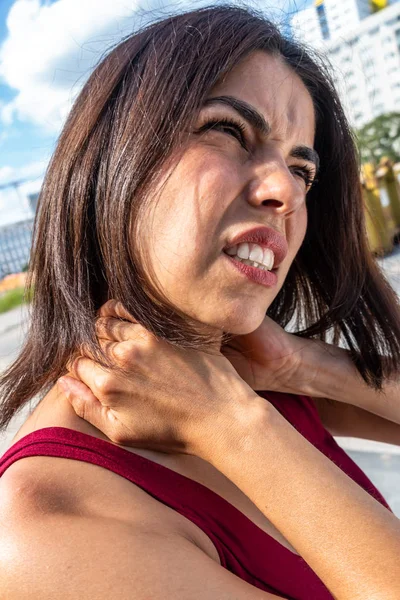 Neck muscle strain. Suffering brunette woman massaging her stiff neck