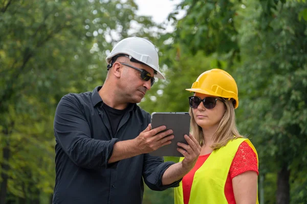 Architect and builder or surveyors discussing about the building location for an ecological forest project