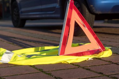 Kırmızı üçgen uyarı işareti ve sarı güvenlik yeleği