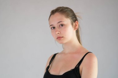 Stüdyoda gri arka planda poz veren çekici genç bir kadın.