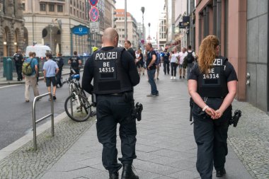 Berlin, Almanya - 13 Haziran 2020: Geri dönen polis ve kadın polis açık hava gösterisi sırasında elleri arkada rahatça yürüyor