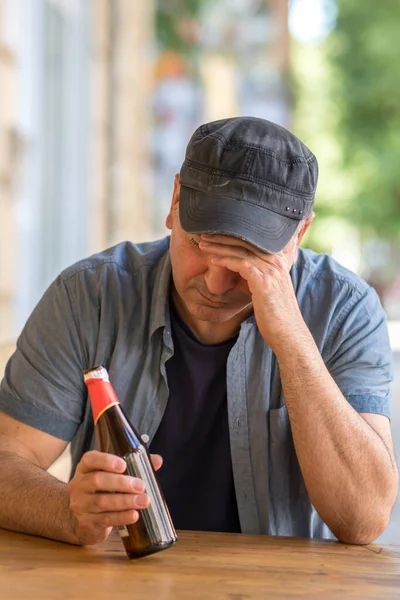 Zamyślony Smutny Człowiek Pochyloną Głową Trzymający Butelkę Piwa Przed Barem — Zdjęcie stockowe