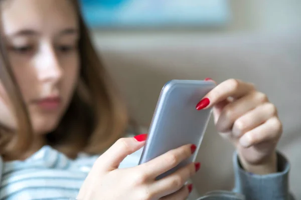 Wasting time online. Young teenage girl looking down at her smartphone. Selective focus