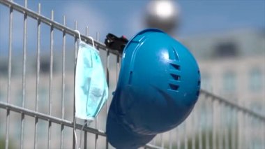 İş güvenliği ve iş yerindeki kötü koşullara karşı koruma. İskelede asılı mavi başlık ve koruyucu cerrahi maske. Önplanda seçmeli odak