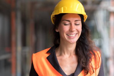 Sarı bir miğfer takan gülümseyen bir fabrika işçisinin portresi.