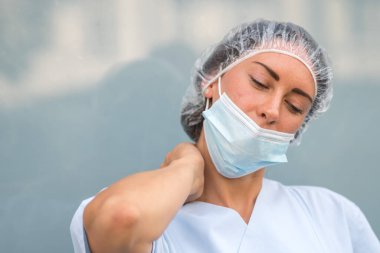 Boyun kası zorlanması. Ağrılı boynuna masaj yapan yorgun ve acı çeken bir doktorun portresi.