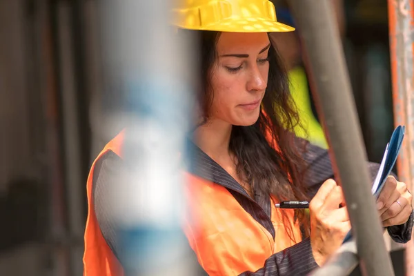 Absorberad Kvinnlig Civilingenjör Med Skyddshjälm Och Väst Som Kontrollerar Kontorsritningar — Stockfoto