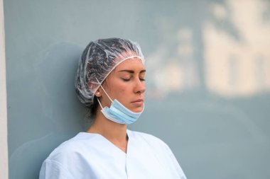 Yorgun bir yüz ifadesiyle dinlenen bir doktorun portresi.