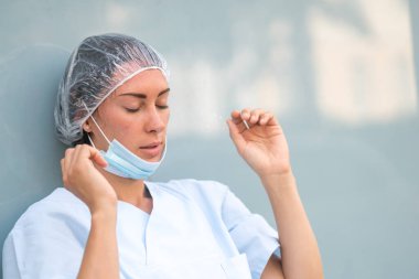 Yorgun bir yüz ifadesiyle dinlenen bir doktorun portresi.