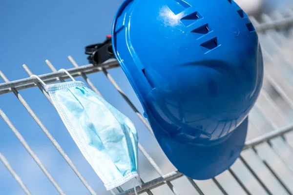 労働安全と職場の悪条件からの保護 青いハード帽子と保護外科用マスク足場にかかっています 選択的焦点 ロイヤリティフリーのストック画像